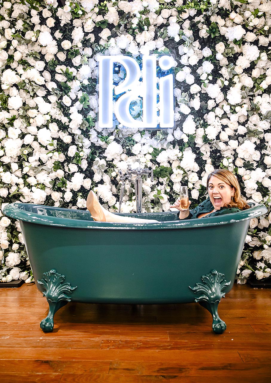 Woman in vintage bathtub with floral backdrop and neon sign Photo by Nashville Interiors