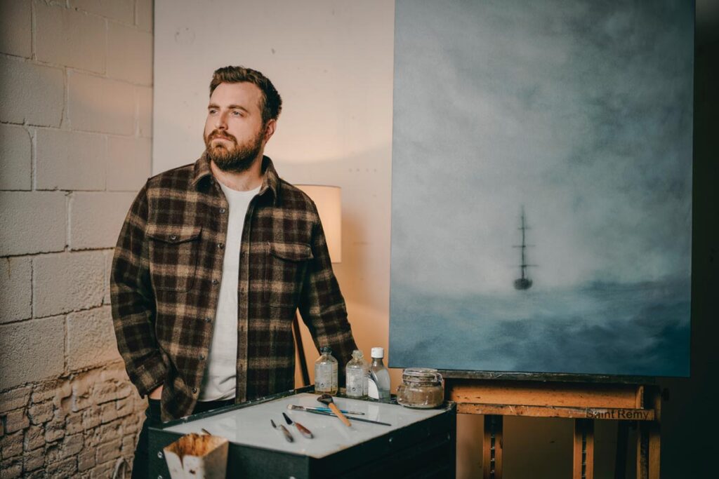 Artist in studio with ocean painting and art supplies © Nashville Interiors