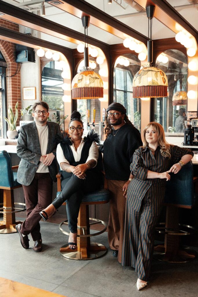 Diverse group of four people posing in stylish bar setting © Nashville Interiors