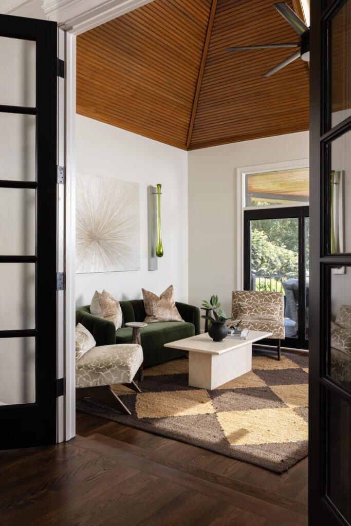 Modern living room with green sofa, abstract art, and large windows © Nashville Interiors