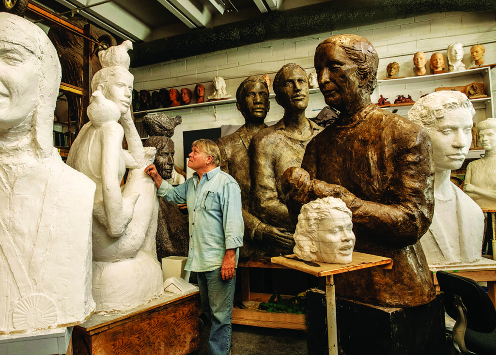 Artist sculpting large statues in a studio filled with various busts and figures Photo by Nashville Interiors