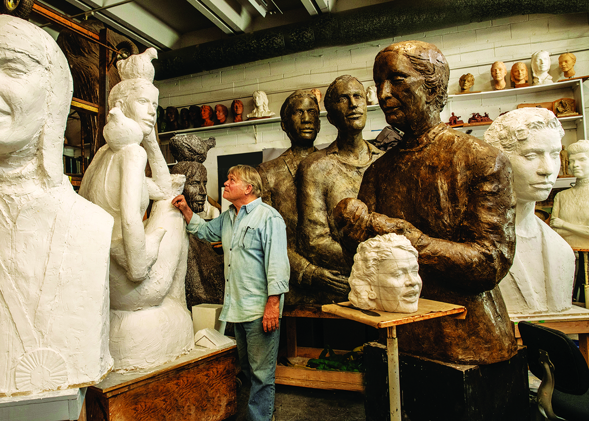 Artist sculpting large statues in a studio filled with various busts and figures Photo by Nashville Interiors