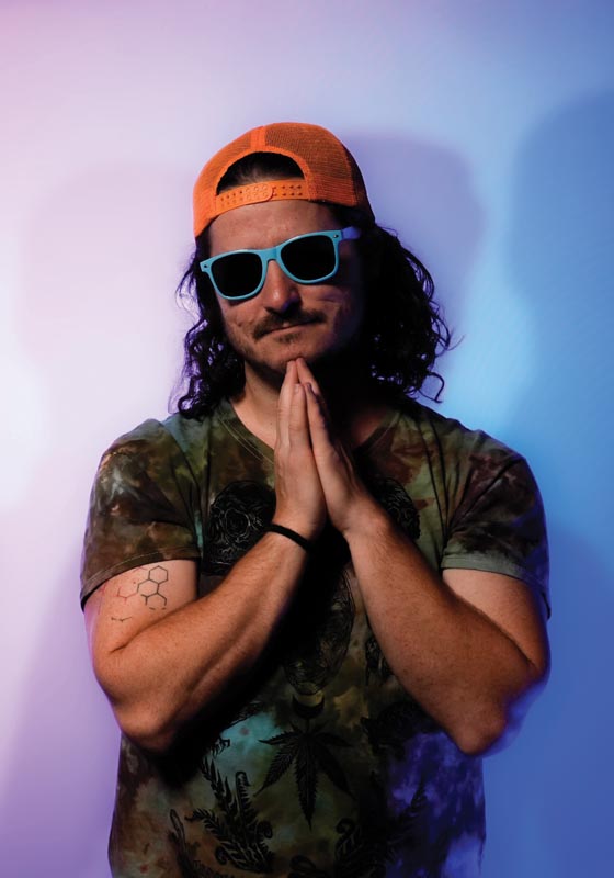 Man with curly hair in sunglasses and cap poses with hands together Photo by Nashville Interiors