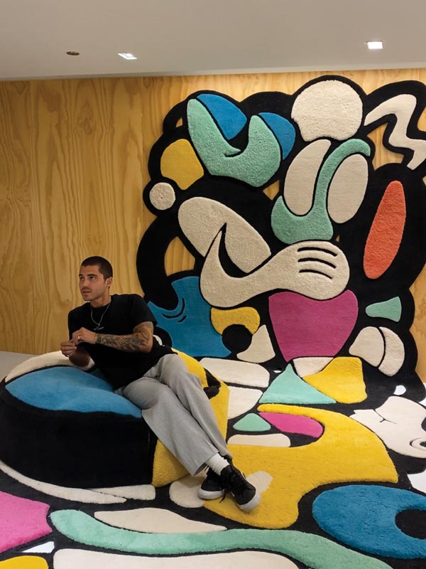 Man sitting on colorful abstract artwork with wooden panel background Photo by Nashville Interiors