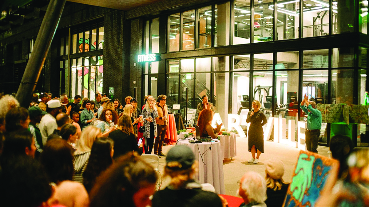 Crowd at gallery exhibition opening with art displays and event speakers Photo by Nashville Interiors