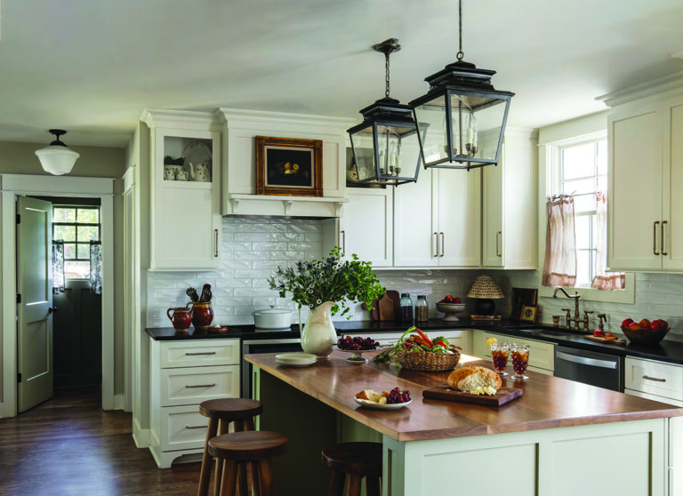Rustic kitchen with island, wooden stools, and hanging lanterns Photo by Nashville Interiors