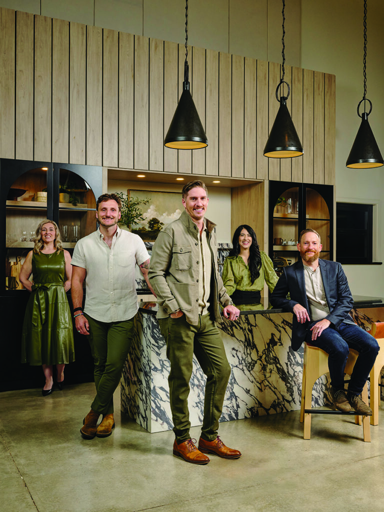 Five people in stylish attire posing in a modern kitchen setting Photo by Nashville Interiors