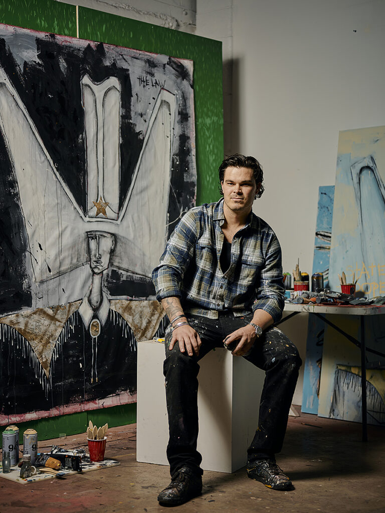 Artist posing in studio with large abstract paintings - Nashville Interiors