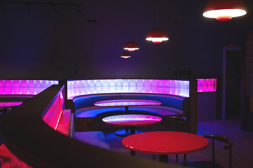 Colorful restaurant booth with neon pink and blue lighting - Nashville Interiors